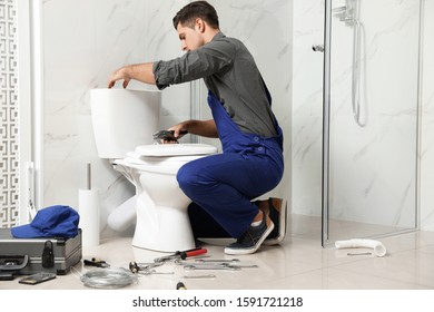 Professional Plumber Working With Toilet Bowl In Bathroom