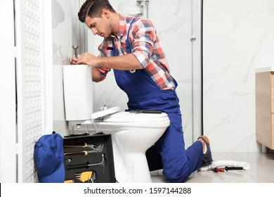 Professional Plumber Working With Toilet Bowl In Bathroom