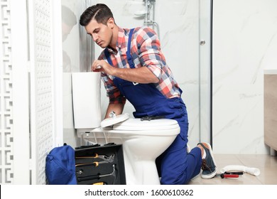 Professional Plumber Working With Toilet Bowl In Bathroom