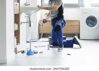 Professional plumbing service: plumber fixing a bathroom sink - Powered by Shutterstock