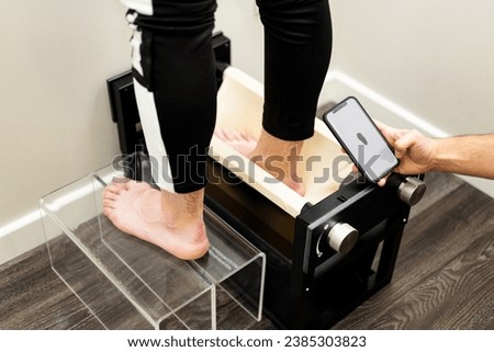 A professional podiatrist templates a patient using a 3D scanner in a physiotherapy clinic. Customized insoles. Use your mobile phone to see the recreation of the foot in three dimensions