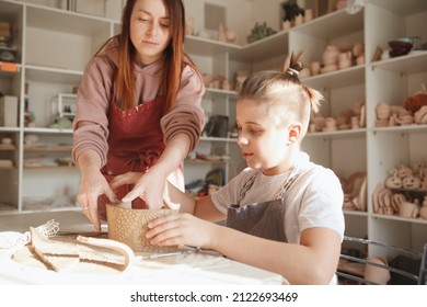 Professional Potter Helping Young Boy Making Tea Cup At Ceramics Class