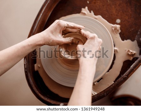 Similar – Young female sitting by table and making clay or ceramic mug