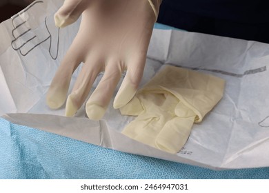 Professional preparing to a procedure wearing a sterile gloves. Gloves in the sterile pack been wears   - Powered by Shutterstock