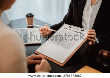 Professional is presenting a contract agreement document on a clipboard, using a pen to highlight sections for a client to review and sign during a consultation