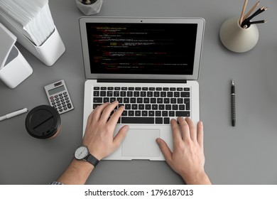 Professional programmer working with laptop at table, top view