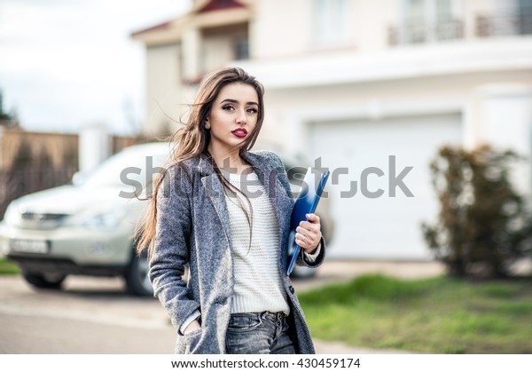 Professional property saleswoman, gesture and\
people concept - happy businesswoman with folder  over property and\
car background