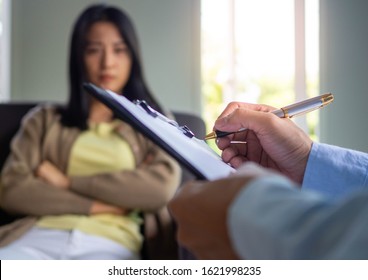 A professional psychiatrist holds a clipboard to note the details of the treatment for mental illness. Depression and hallucinations due to addiction.