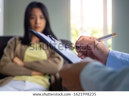 A professional psychiatrist holds a clipboard to note the details of the treatment for mental illness. Depression and hallucinations due to addiction.