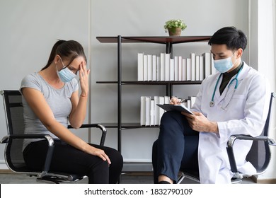 Professional Psychologist Male Wearing Protective Medical Face Mask Conducting A Consultation And Making Notes While Talking To Stressful Woman In Face Mask During Coronavirus Or COVID 19 Outbreak