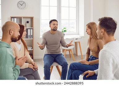 Professional psychotherapist leading group of young adults, helping male and female patients to cure mental health problems through group therapy activities. Group therapy session concept.  - Powered by Shutterstock