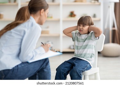 Professional Psychotherapist Trying To Talk To Difficult Kid, Grumpy Little Boy Covering Ears And Frowning Nose, Ignoring Psychologist During Session