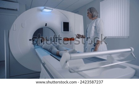 Professional radiologist lays female patient in MRI or CT or PET scan machine. Doctor conducts check up procedure in clinic with advanced medical technologies. High-tech modern medical equipment.