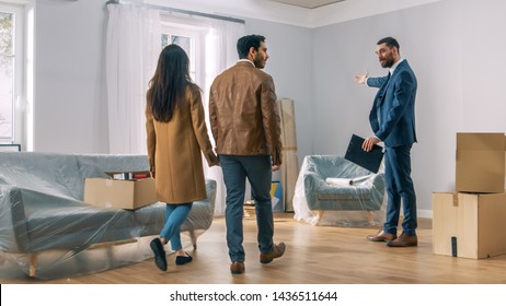 Professional Real Estate Agent Shows Bright New Apartment to a Young Couple. Successful Young Couple Ready to Become Homeowners. Spacious Bright Home with Big Windows. - Shutterstock ID 1436511644