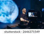 A professional recording setup capturing a DJ performing against a blue digital moon backdrop.