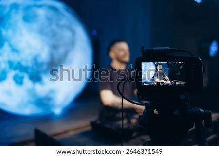 A professional recording setup capturing a DJ performing against a blue digital moon backdrop.