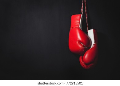 Professional red boxing gloves hanging on black background with copy space.