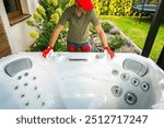 A professional in red gloves inspects and prepares a hot tub in a garden, ensuring everything is set for installation. The area is well-lit and showcases greenery.