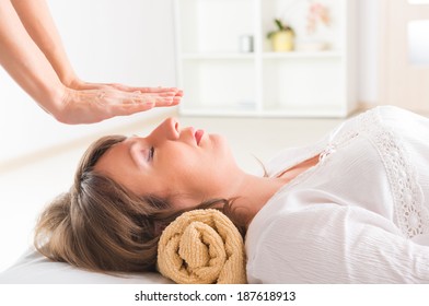 Professional Reiki healer doing reiki treatment to young woman