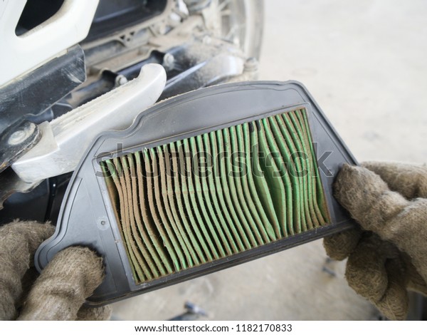 Professional repair service removing a dirty old air\
filter motorcycle\
used