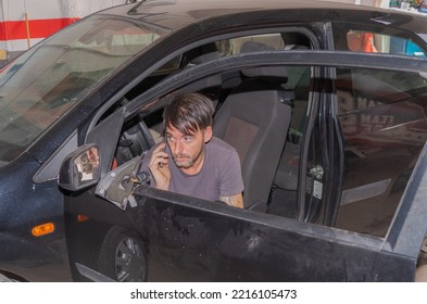 The Professional Repairer, Sitting In The Car With The Door Open, Calls The Owner Of The Car On His Smartphone And Explains That He Is Repairing The Inside Of The Door In His Workshop In Granada.