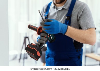 Professional repairman changing the drill bit, he is inserting the drill bit on the drill chuck