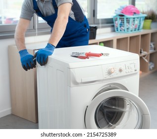 Professional repairman fixing a broken washing machine, home repair concept