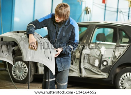 professional repairman worker in automotive industry sanding plastic body car bumper