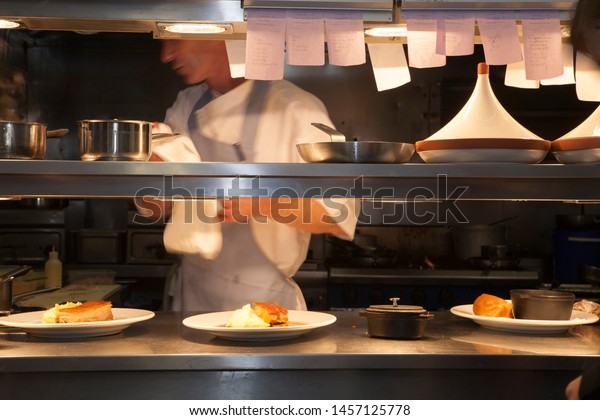 Professional restaurant kitchen with\
food being prepared and set on kitchen pass for waiting\
staff.