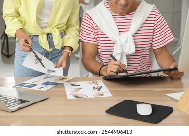 Professional retoucher with colleague working at desk in photo studio, closeup - Powered by Shutterstock