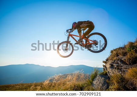 Professional rider is jumping on the bicycle, with background of blue sky. Sunny summer day.