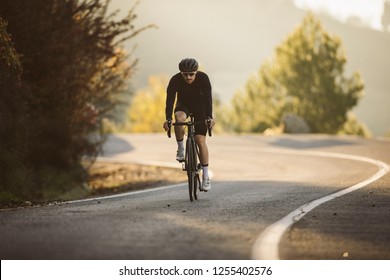 Professional road bicycle racer in action. Men cycling mountain road bike at sunset.