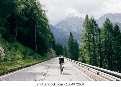 Professional road cyclist on fast and light carbon bicycle descends mountain road in Alps Dolomites. Fit and athletic man on recreational ride trip or training camp, enjoy time outdoors on bike - Powered by Shutterstock