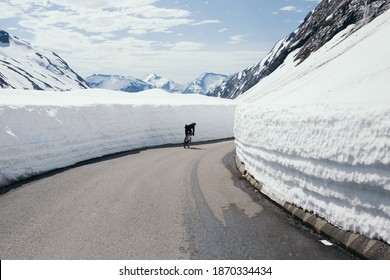 Professional road cyclist on winding mountain pass road in winter. Cycling on road covered in snow. Beginning or end of season. Road cycling in winter