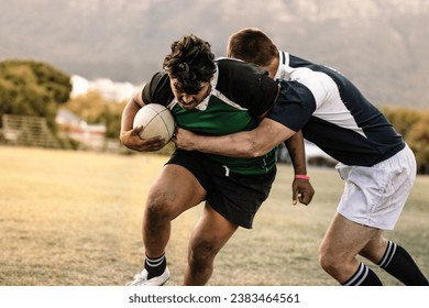 Professional rugby players striving to get the ball during the game. Rugby player with ball is blocked by the opposite team player at ground. - Powered by Shutterstock