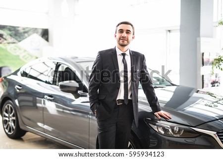 Professional salesman smiling in front of a new car