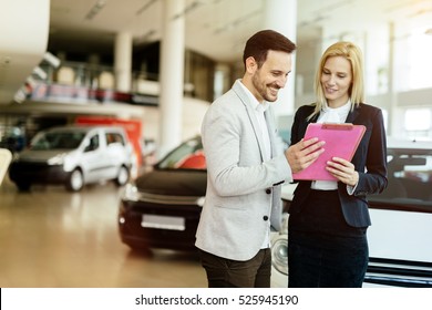 Professional salesperson selling cars at dealership to buyer