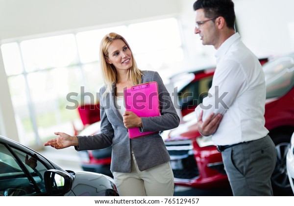 Professional salesperson selling cars at dealership\
to buyer