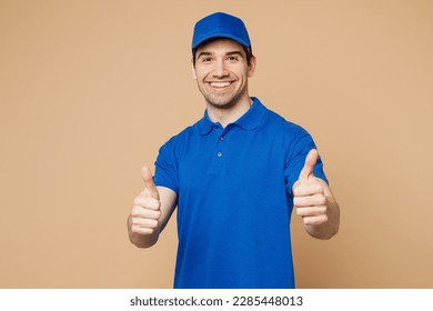 Professional satisfied delivery guy employee man wear blue cap t-shirt uniform workwear work as dealer courier showing thumb up like gesture isolated on plain light beige background. Service concept - Powered by Shutterstock