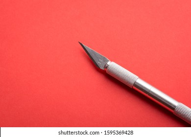 Professional Scalpel For Cutting Paper, Plastic, Wood On A Red Paper