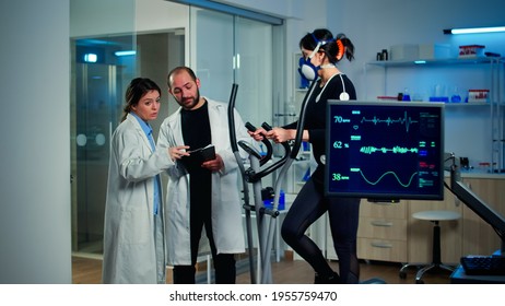 Professional scientist analysing EKG results looking at monitor examining heart rate of athlete. Team of researchers monitoring endurance, vo2 max, psychological resistance in science sport laboratory - Powered by Shutterstock