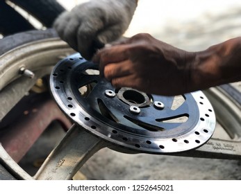 Professional are screwing the iron screw, on disk brake with wheel of motorcycle for repair, Bangkok, Thailand, 2018. - Shutterstock ID 1252645021