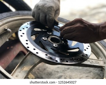 Professional are screwing the iron screw, on disk brake with wheel of motorcycle for repair, Bangkok, Thailand, 2018. - Shutterstock ID 1252645027