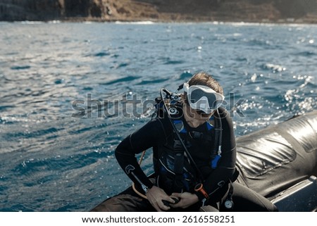 Professional scuba diver checking diving equipment while sitting on inflatable boat, preparing for diving exploration in the sea
