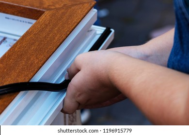 Professional sealing a window frame. Rubber insulation  in a plastic window. Concept improvement of sealing, sound insulation, thermal insulation of windows and doors. Hands applying rubber strip. - Shutterstock ID 1196915779