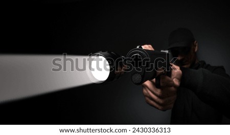 Professional security guard or policeman with flashlight and gun in dark room