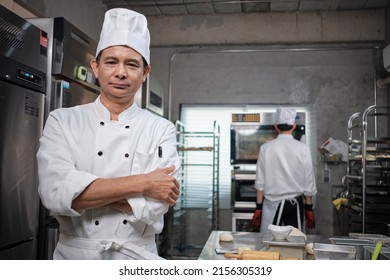 Professional senior Asian male chef in white cooking uniform, food occupation looks at camera, arms crossed, expertise in commercial pastry culinary jobs, catering restaurant kitchen. - Powered by Shutterstock