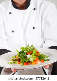 Professional Senior Female Chef In Kitchen Presenting Salad