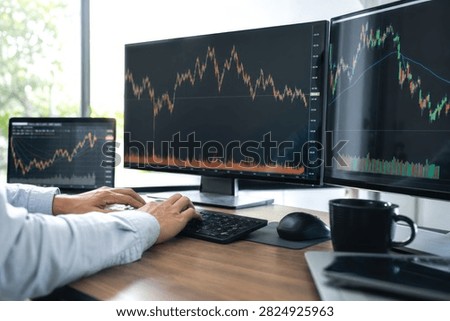 Professional senior trader analyzing real-time stock market charts on dual monitors in bright modern home office with coffee mug and mouse