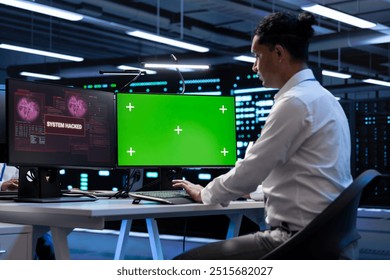 IT professional in server hub using mockup computer, trying to protect hardware from hacker. Cybersecurity expert in high tech data center workplace trying to fix security breach on green screen PC - Powered by Shutterstock